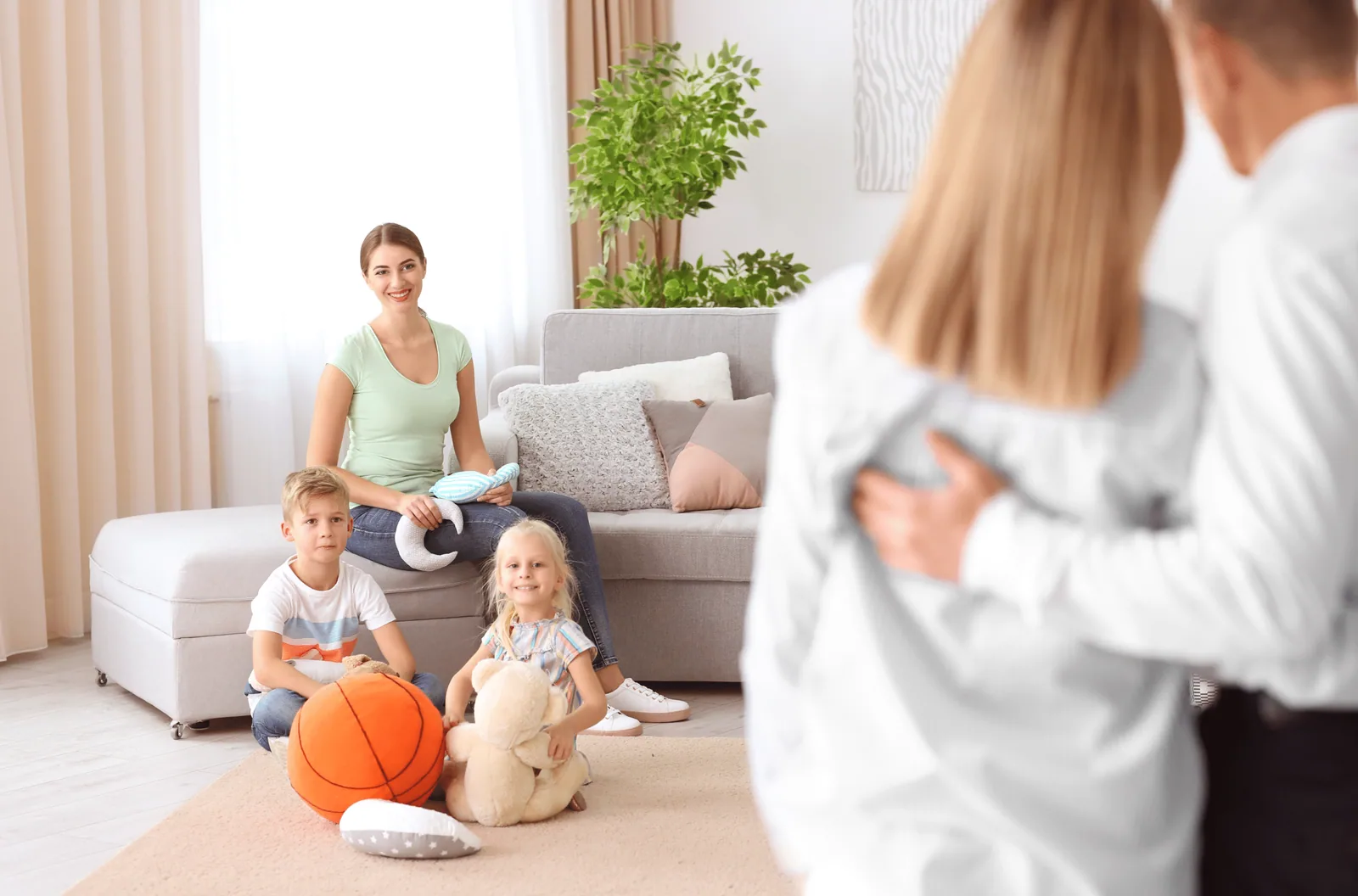 A therapist and two children playing on the floor of a family living room during an in-home session