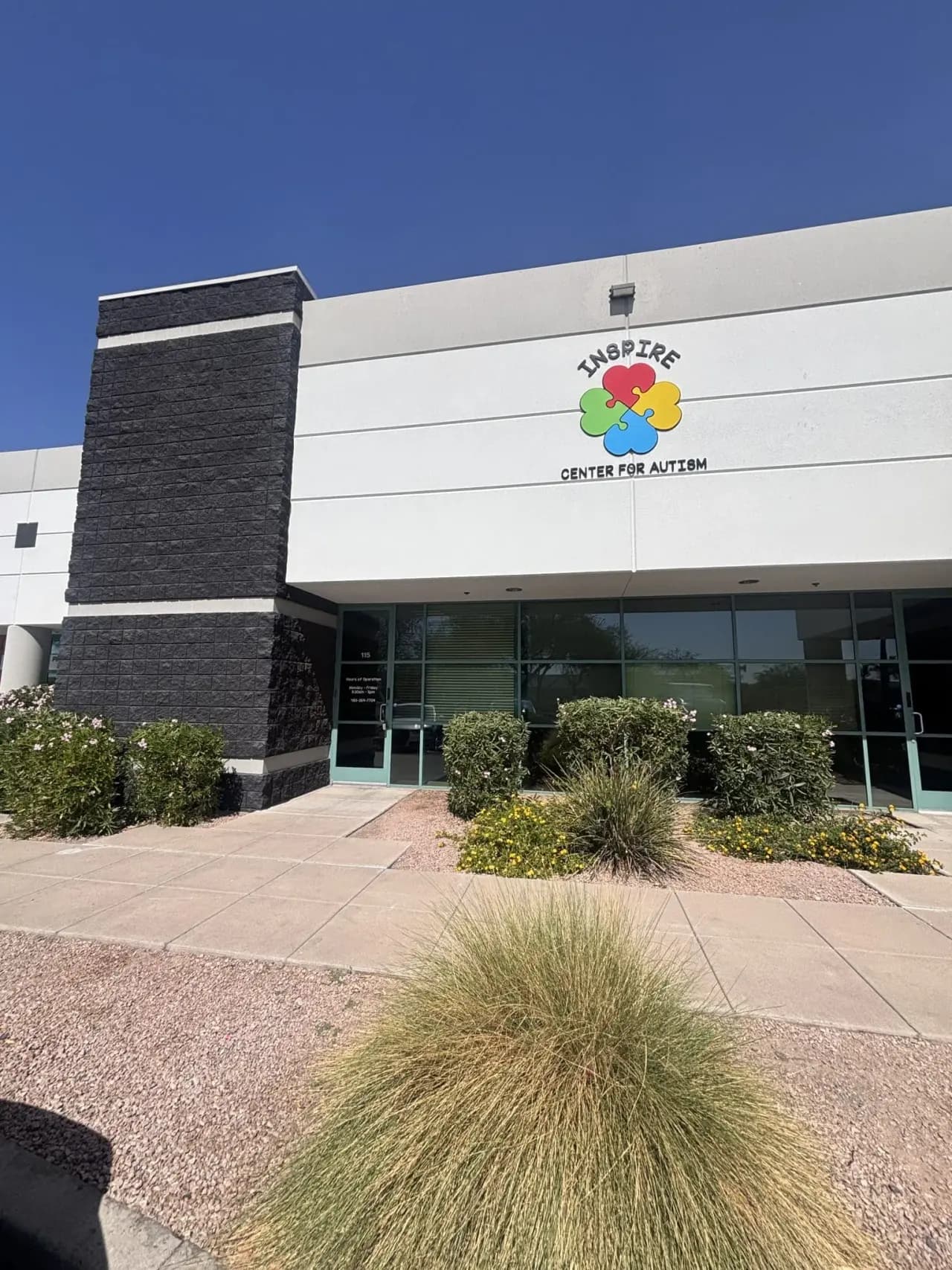 The entrance of Inspire Center for Autism in Mesa — the Suite 115 glass door beneath the colorful Inspire flower sign